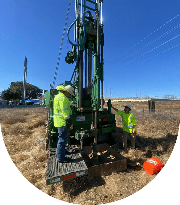 Two workers operate a drilling rig.