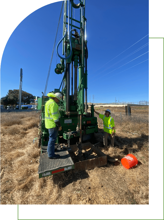 Two workers operating a drilling rig.