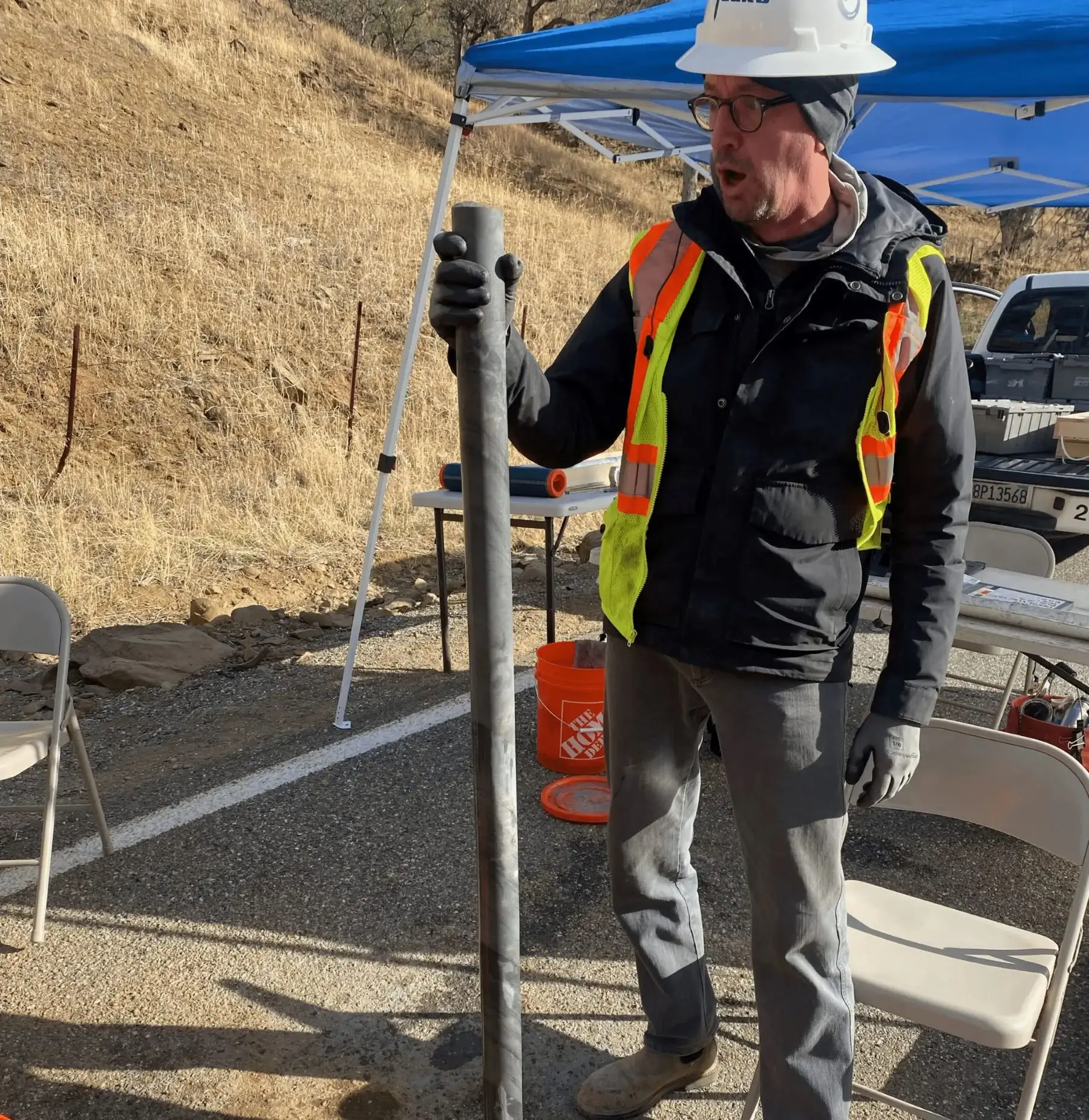 Man in safety gear holding metal pipe.